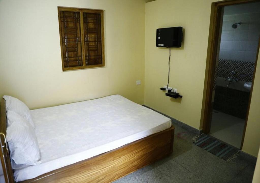 a bedroom with a bed and a shower and a television at Nest Guest House in Bhubaneshwar