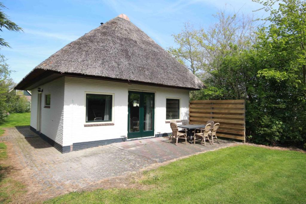 a small hut with a thatched roof with a table and chairs at Nieuwlanderweg 69 in De Waal