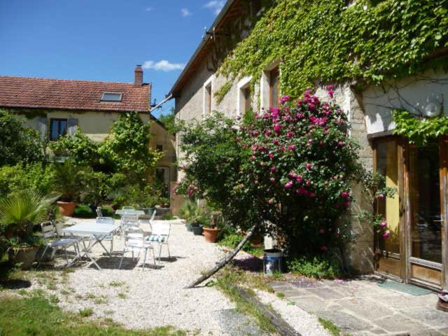 un jardín con mesas y sillas junto a un edificio en La grange, en Grancey-le-Château