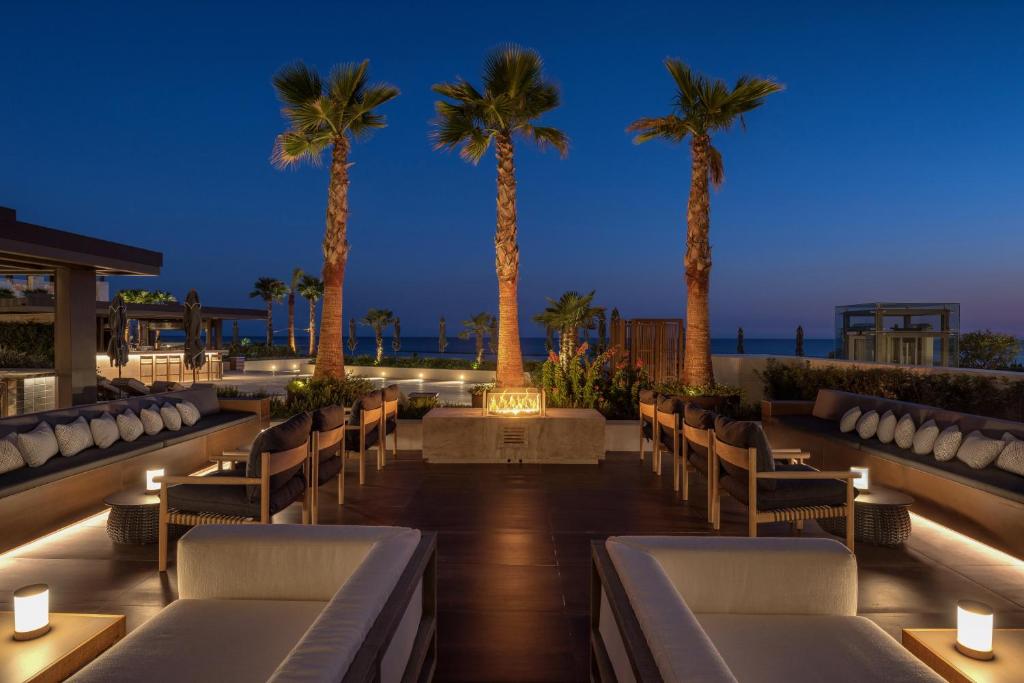 a hotel patio with chairs and palm trees at night at Amara - Sea Your Only View™ in Limassol