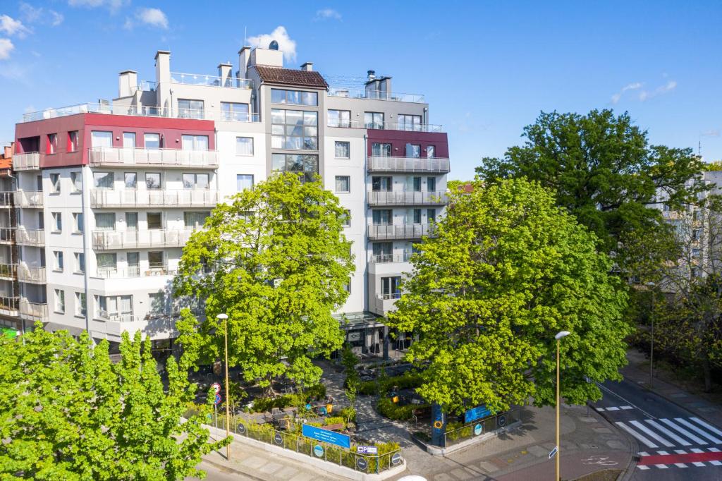 ein großes weißes Gebäude mit Bäumen davor in der Unterkunft Apartamenty Rondo in Świnoujście