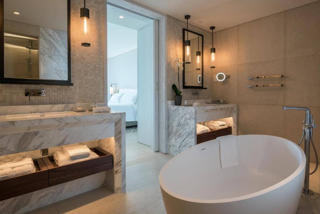 a bathroom with a white tub and a sink and a tub at Amara - Sea Your Only View™ in Limassol