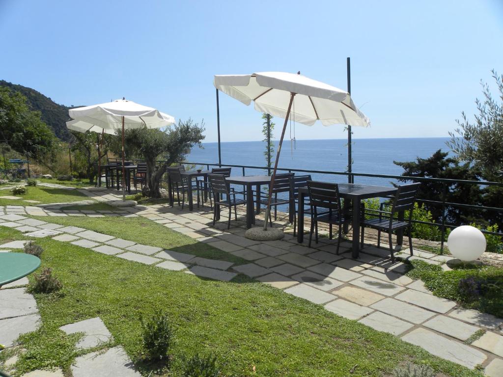 eine Reihe von Tischen und Stühlen mit Sonnenschirmen und dem Meer in der Unterkunft Corte Del Gallo in Corniglia