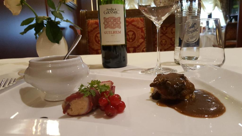 a white plate with food on a table with a bottle of wine at Hotel Re'ser Stuff in Roeser