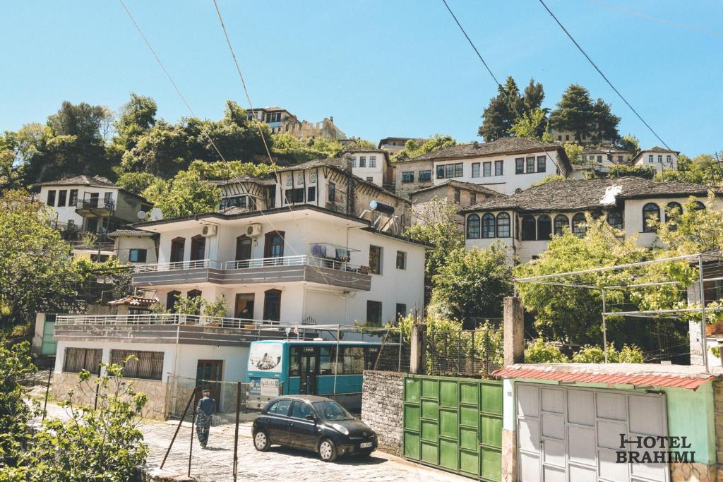 une voiture garée devant une maison sur une colline dans l'établissement Hotel Brahimi, à Gjirokastër