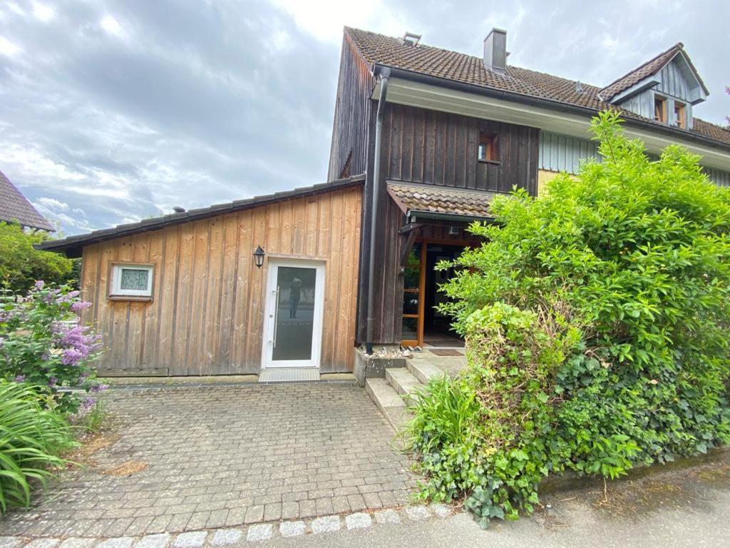 a wooden house with a white door and some bushes at FeWo Henke in Gailingen