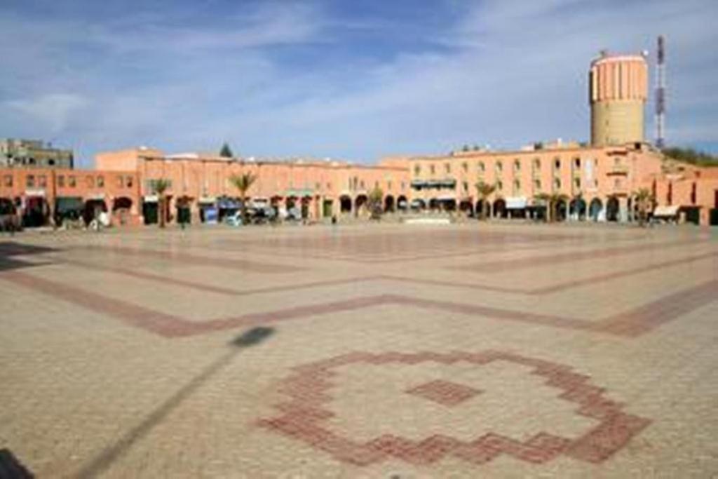 un grand bâtiment en briques avec un symbole rouge au sol dans l'établissement Hotel Bab Sahara, à Ouarzazate