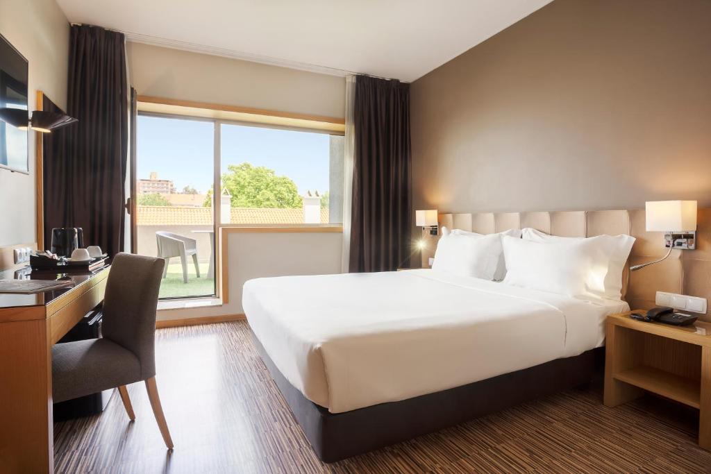 a hotel room with a bed and a desk and a window at HF Tuela Porto in Porto