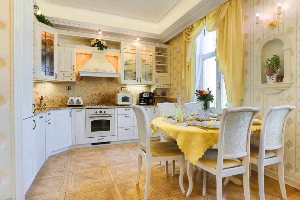 cocina con armarios blancos, mesa y sillas en Apartmán Nostalgia en Karlovy Vary