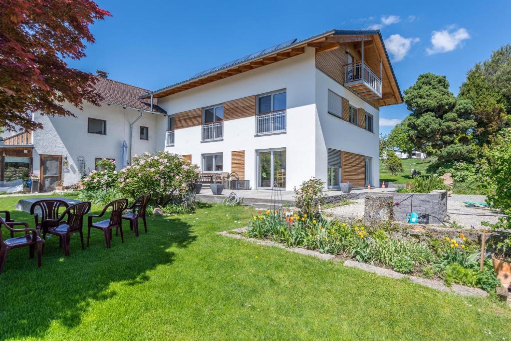 uma casa com um quintal com mesas e cadeiras em Ferienwohnung Rudi em Taching am See