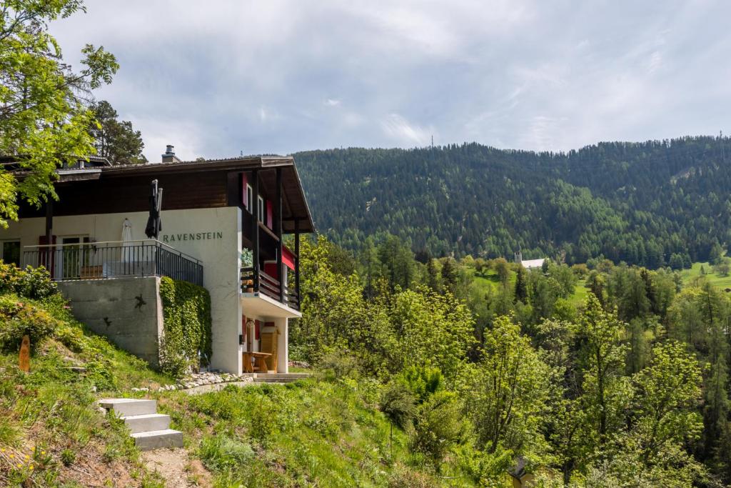 a building on the side of a hill with trees at Chalet Ravenstein in Fiesch