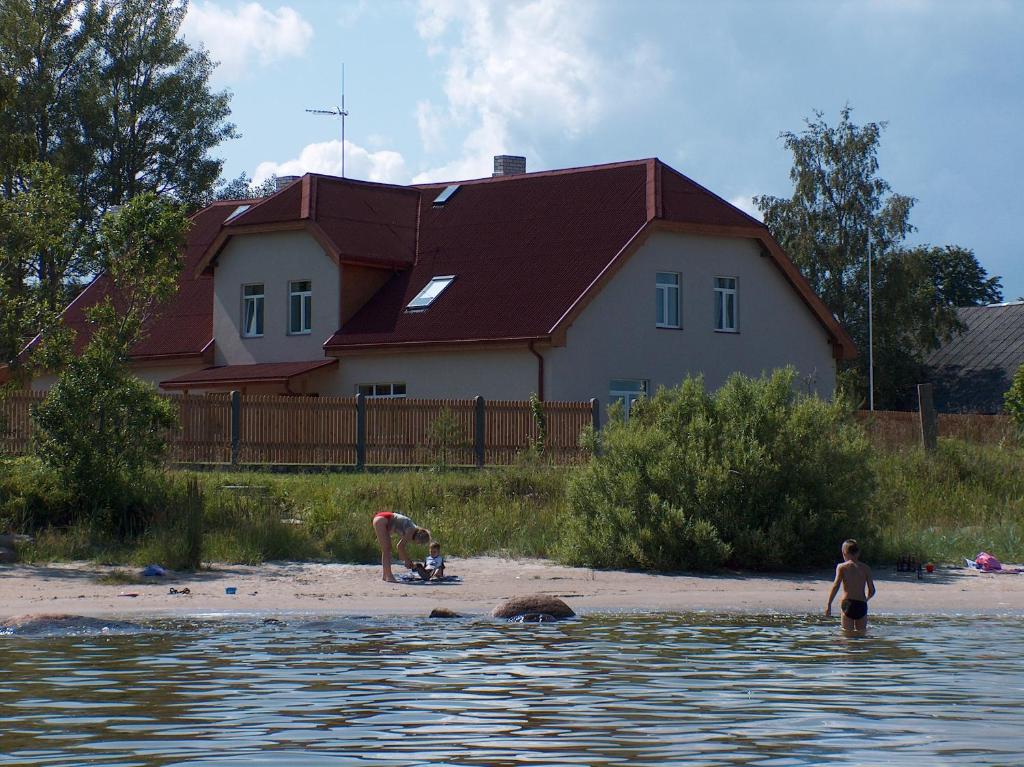a couple of people on a beach with a house at Viesu nams Zivtiņi in Kaltene