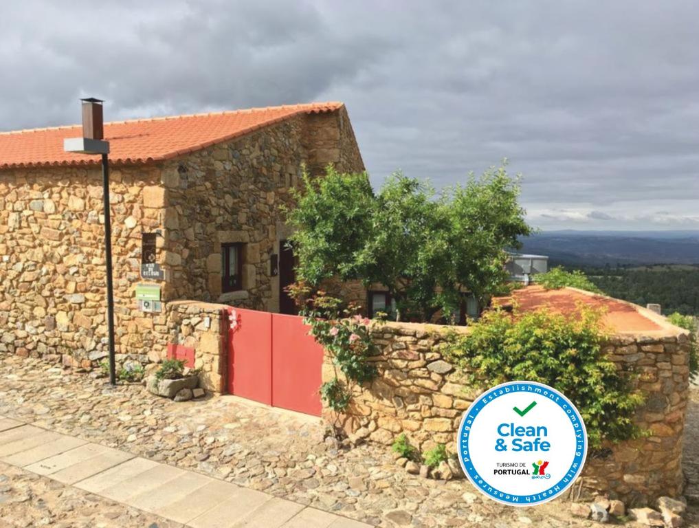 un edificio de piedra con un cartel delante en Casa da Amendoeira, en Castelo Rodrigo