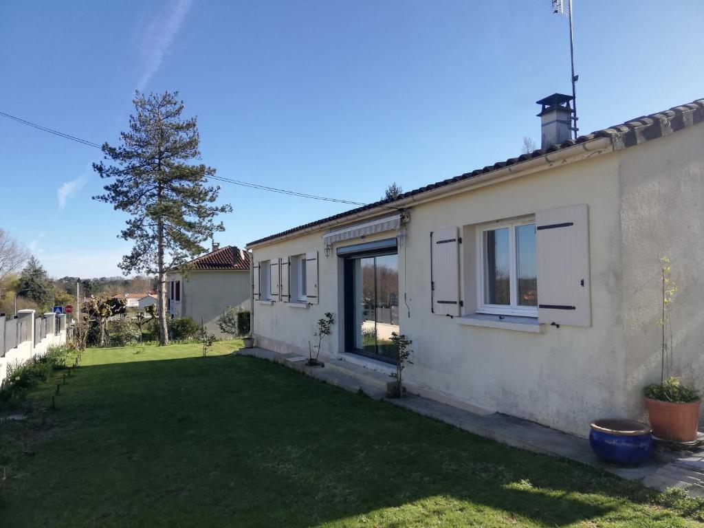 a white house with a yard with a grass yard at La Petite Source in Montendre