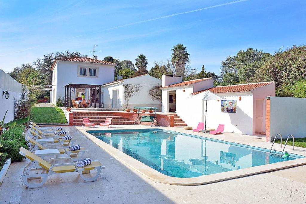 a swimming pool with lounge chairs and a house at Villa Flora in Sesimbra