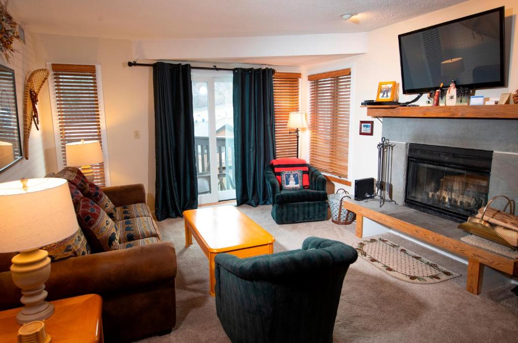 un soggiorno con camino e TV di Mountain Lodge at Okemo-1Br Fireplace & Updated Kitchen condo a Ludlow