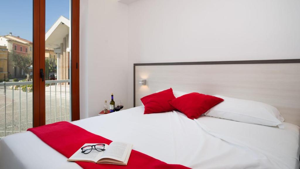 sypialnia z białym łóżkiem z czerwonymi poduszkami i książką w obiekcie Viverenumana w mieście Numana