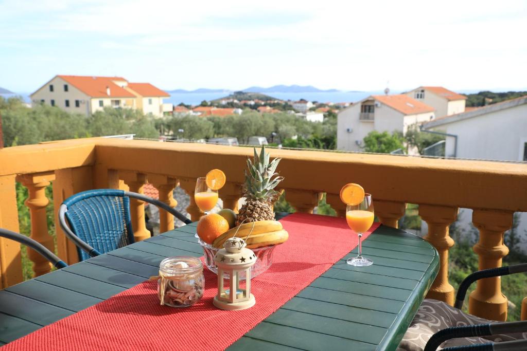 een blauwe tafel met drankjes en ananas op een balkon bij APARTMANI SARLIJA in Pakoštane
