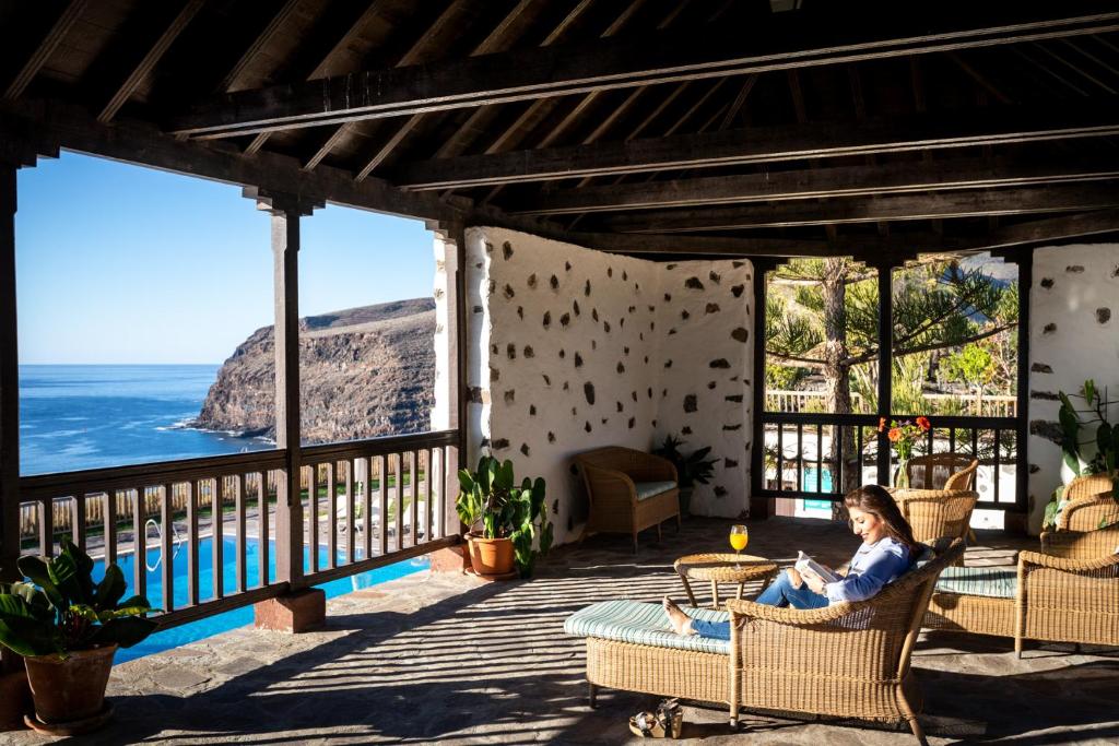 a woman sitting in a chair on a porch overlooking the ocean at Parador de La Gomera in San Sebastián de la Gomera