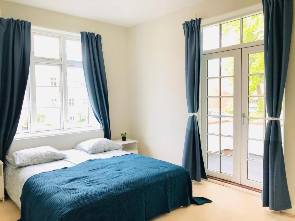 een slaapkamer met een bed met blauwe lakens en ramen bij aday - 4 Bedroom - Modern Living Apartment - Aalborg in Aalborg