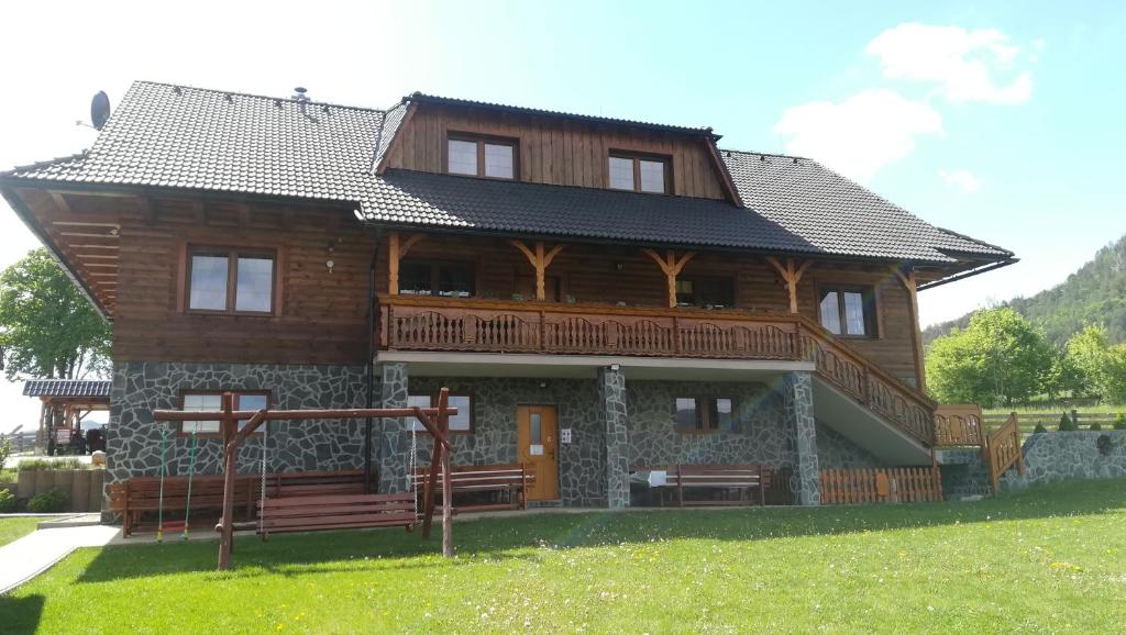 une grande maison en bois avec des bancs devant elle dans l'établissement Rekreačné zariadenie Chmelisko, à Pružina