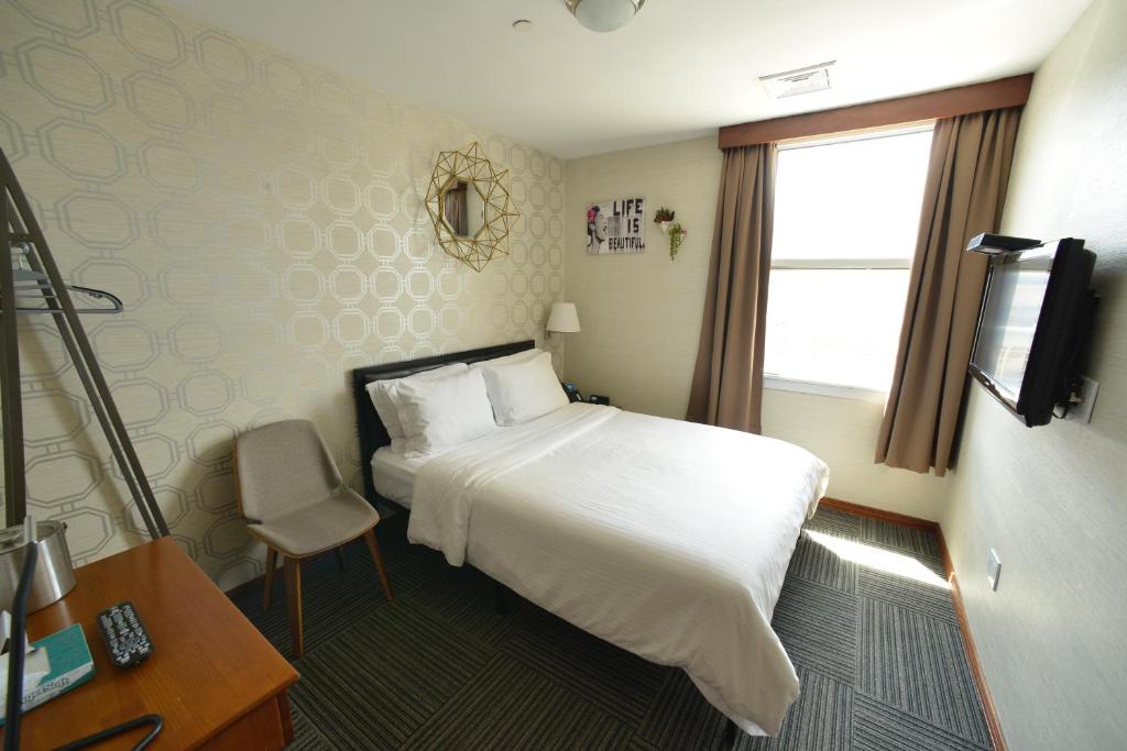 Pokój hotelowy z białym łóżkiem i oknem w obiekcie Hotel Mimosa w Nowym Jorku