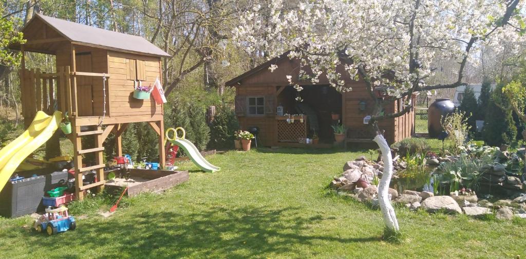 un patio trasero con una casa de juegos y un parque infantil en Domeczek Sami, en Łunowo