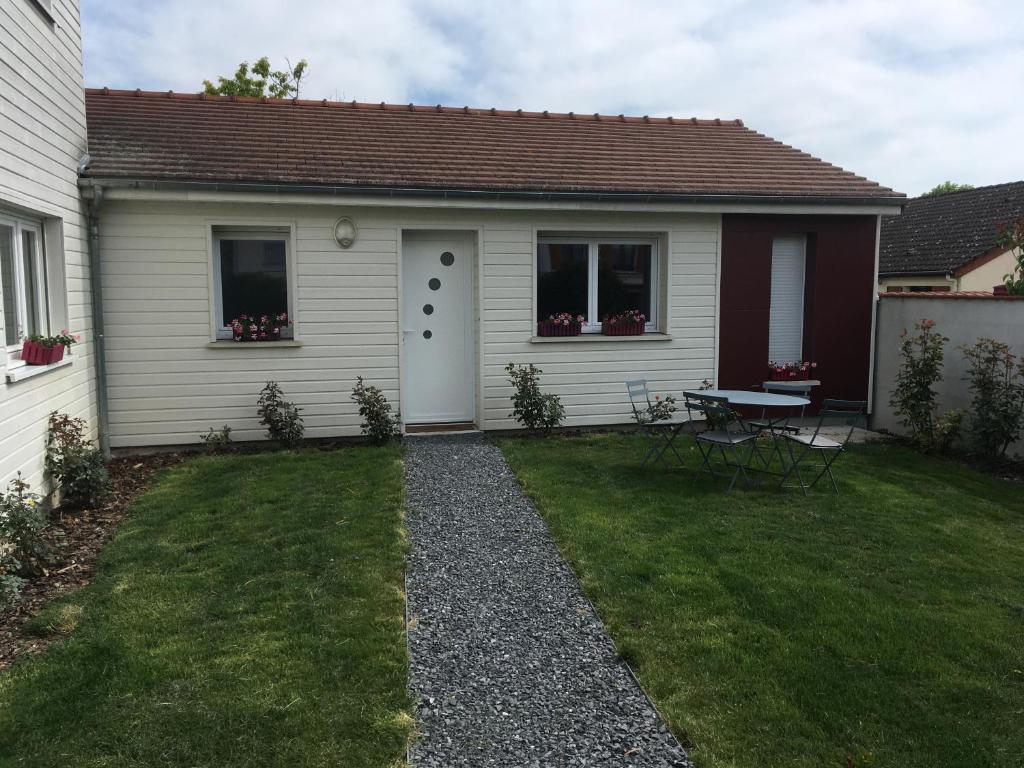 een klein wit huis met een tafel in een tuin bij Maison Mitoyenne in Taissy