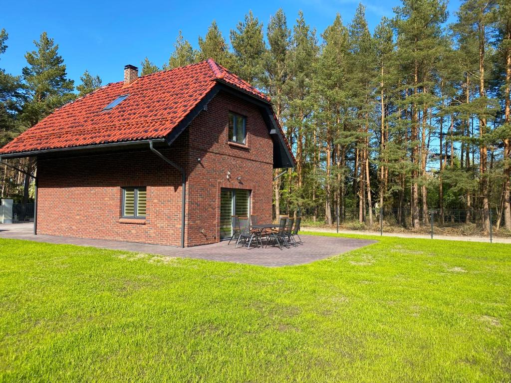 una casa de ladrillo con techo rojo en un parque en Gintarinis pajuris en Karklė
