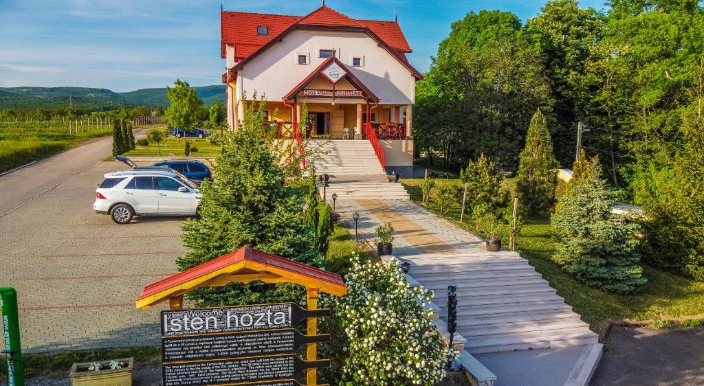 a house with a car parked in a parking lot at Borhotel Sziluett Farkasmály in Gyöngyös