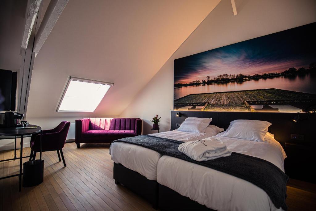 a bedroom with a bed with a large painting on the wall at Boetiekhotel Burgemeesterhuys in Beringen
