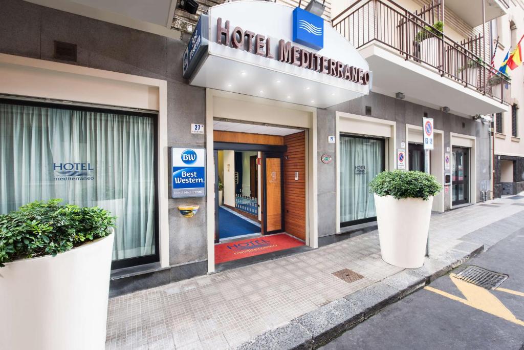 ein Hotel mit zwei großen Topfpflanzen davor in der Unterkunft Best Western Hotel Mediterraneo in Catania