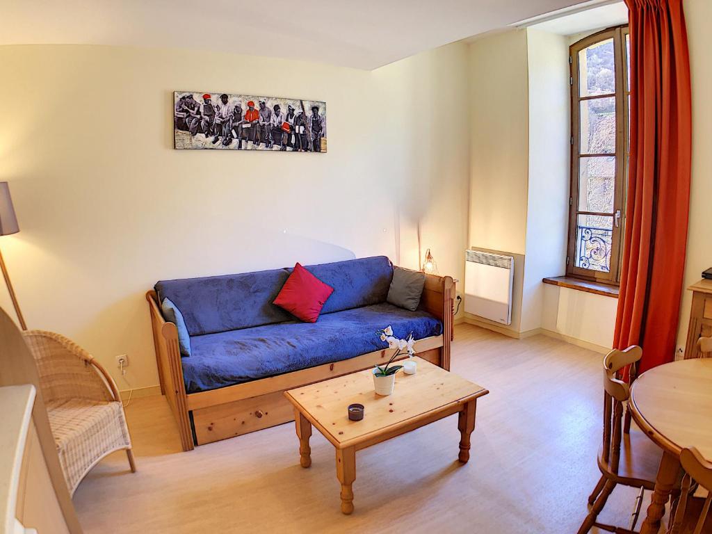 a living room with a blue couch and a table at Appartement 208 Résidence du Grand Hotel Aulus-les-Bains in Aulus-les-Bains