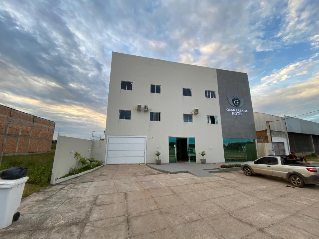 a white building with a car parked in front of it at GRAN PARADA HOTEL in Castanhal