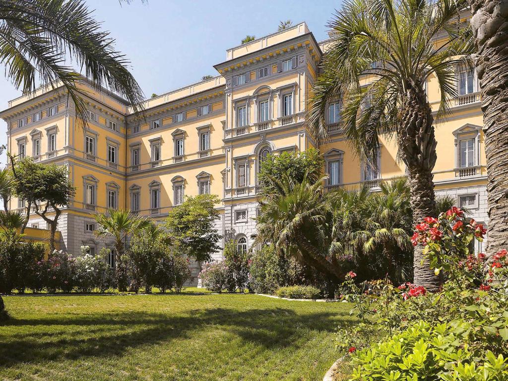 a large building with trees and palm trees at Grand Hotel Palazzo Livorno MGallery Collection in Livorno