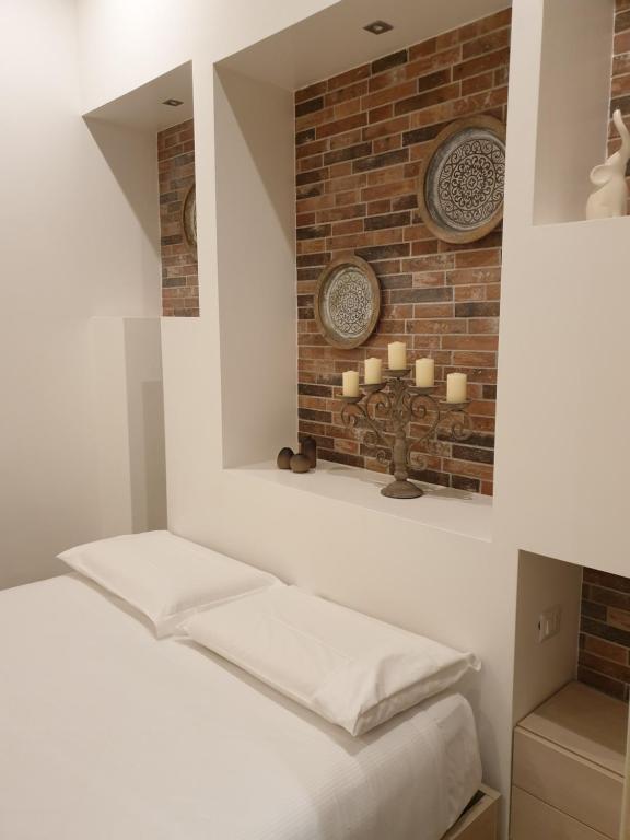 um quarto com uma parede de tijolos e uma cama com velas em Kibilù - Viale Bligny - Porta Romana - Università Bocconi em Milão