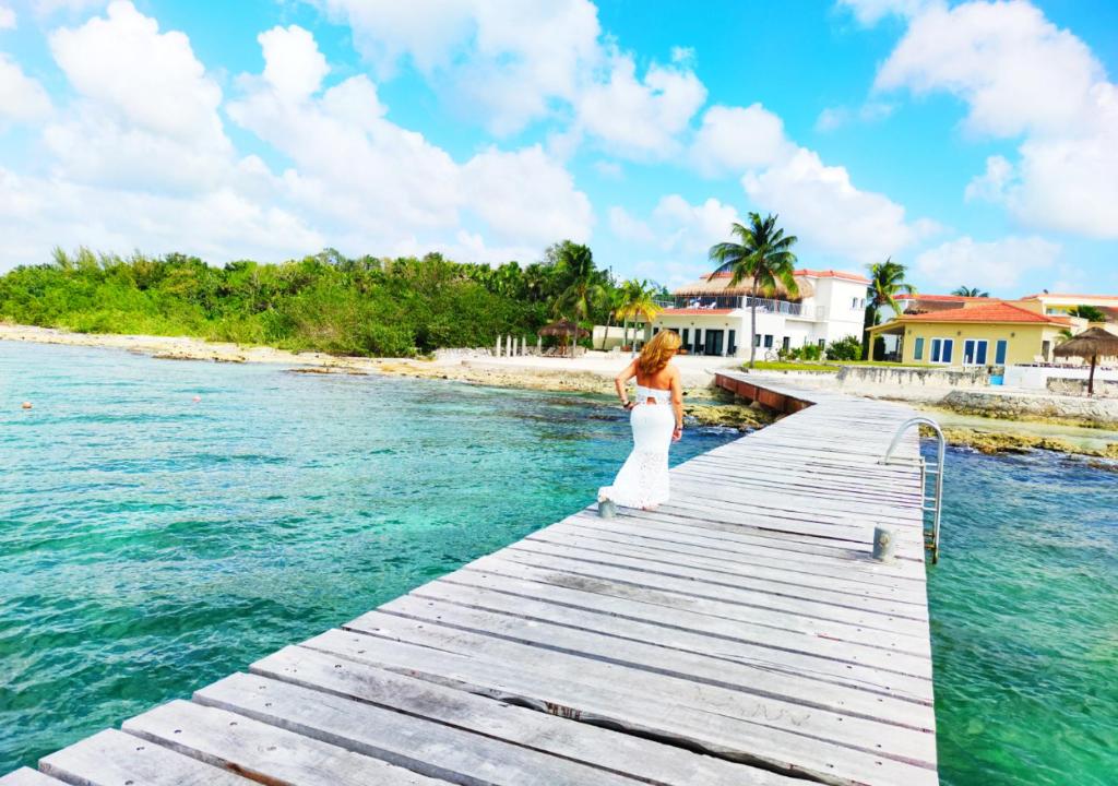 a woman in a white dress standing on a dock in the water at The Queen of Cozumel Beach House -Luxury Beachfront Villa- MILLION DOLLARS VIEW in Cozumel