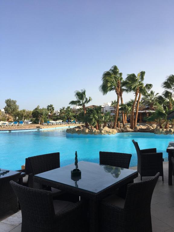 a table and chairs in front of a swimming pool at Delta Sharm Apartments with free Internet Wi-Fi in Sharm El Sheikh