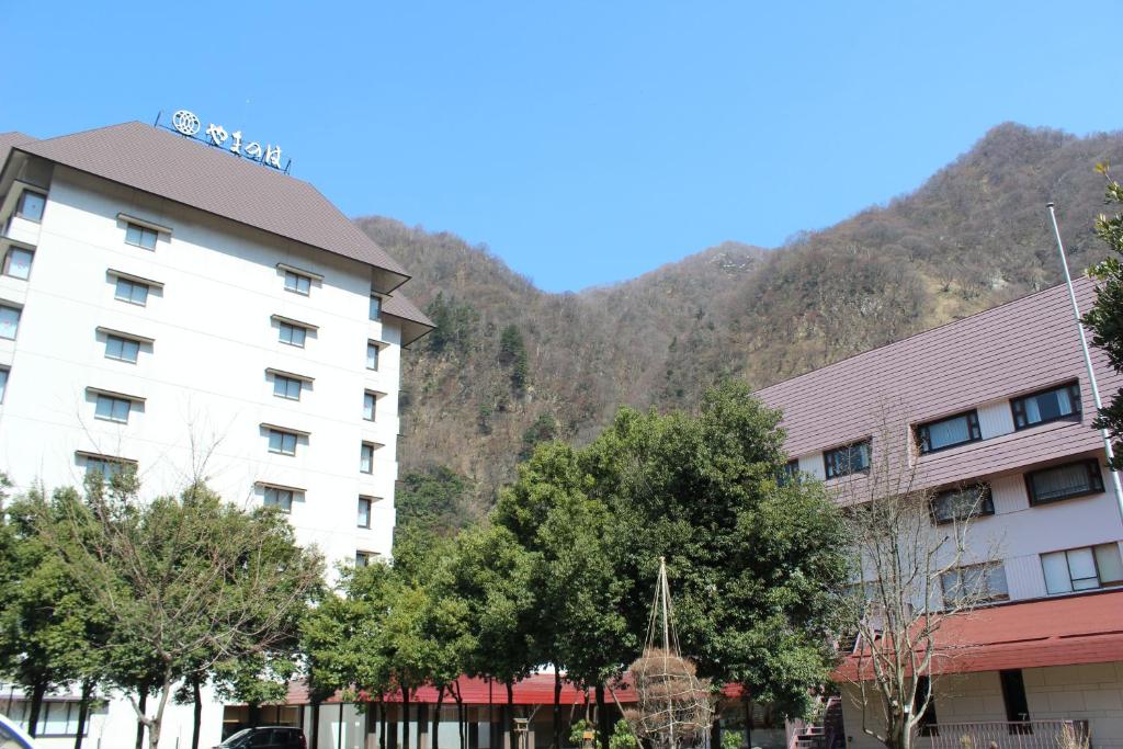 ein Hotel mit einem Berg im Hintergrund in der Unterkunft Kurobe Unazukionsen Yamanoha in Kurobe