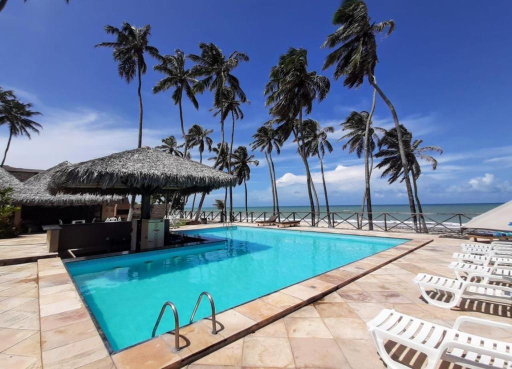 uma piscina com palmeiras e o oceano em ECO PARADISE _ CUMBUCO BOUTIQUE em Cumbuco