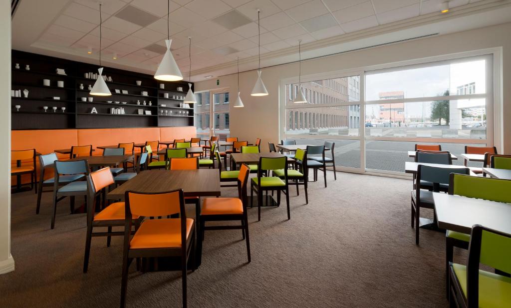 uma cafetaria com mesas e cadeiras e uma grande janela em Holiday Inn Express Antwerpen City North by IHG em Antuérpia