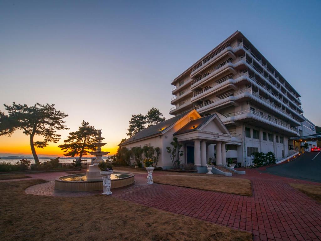 玉野市にあるダイヤモンド瀬戸内マリンホテルの夕日を背景に見える大きなアパートメントです。
