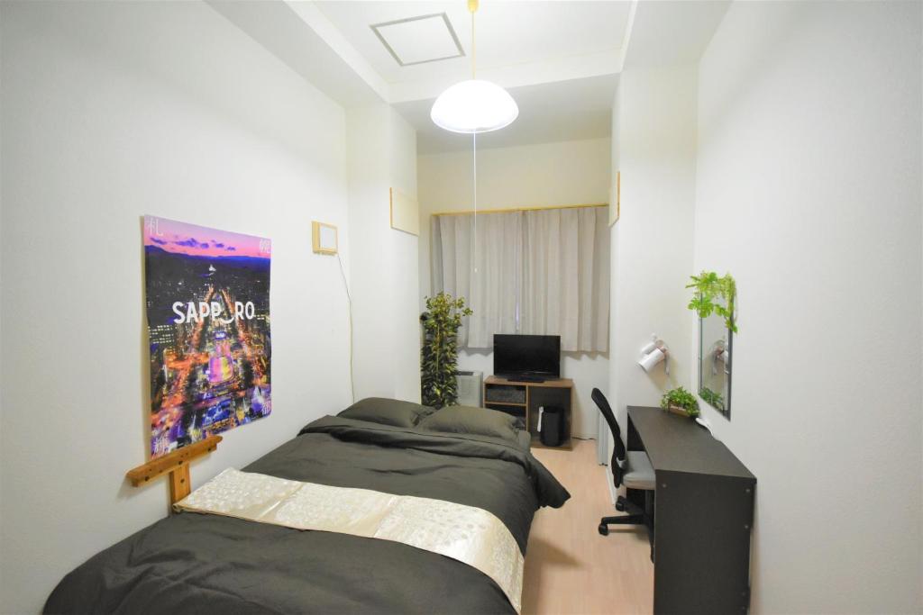 a room with two beds and a desk and a tv at KIYAZA Road Sapporo in Sapporo