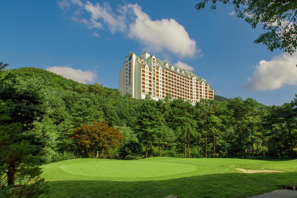un parcours de golf avec un bâtiment en arrière-plan dans l'établissement Yangji Pine Resort, à Yongin