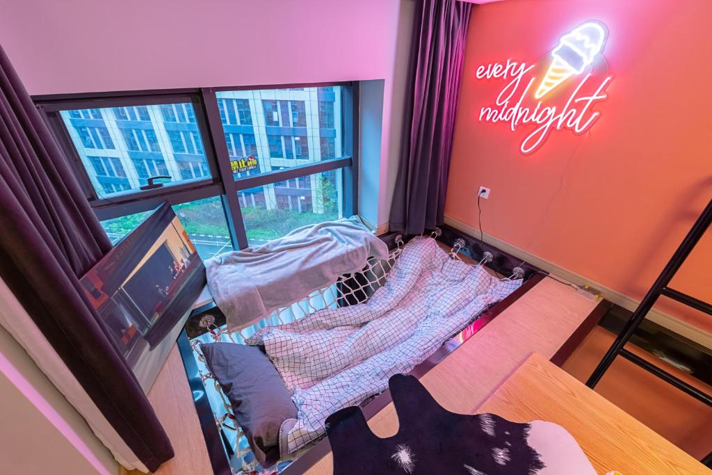 a small room with a bed and a window at loft Apartment with slide hammock with movie viewing in Hangzhou