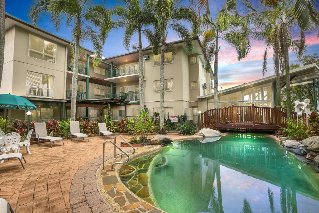 a swimming pool in front of a building with palm trees at Koala Court Holiday Apartments in Cairns