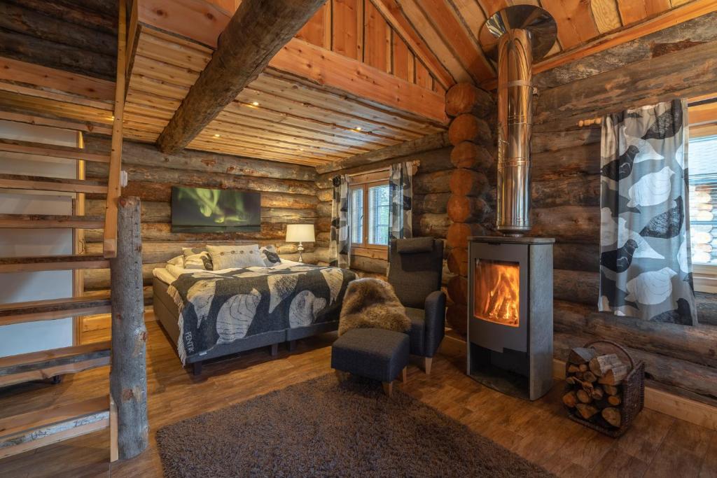 a log cabin bedroom with a bed and a fireplace at Wilderness Hotel Nellim & Igloos in Inari