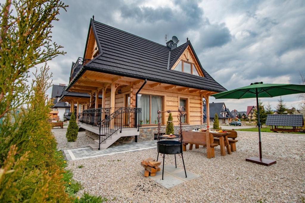 a log cabin with a table and an umbrella at Domki Pod Jemiołą in Zakopane