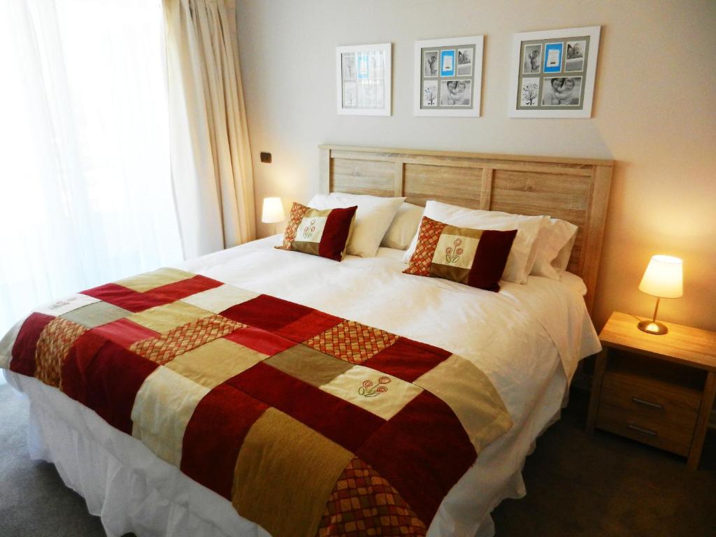 a bedroom with a large bed with a colorful quilt at Apartamentos Terrazas de Talca in Talca