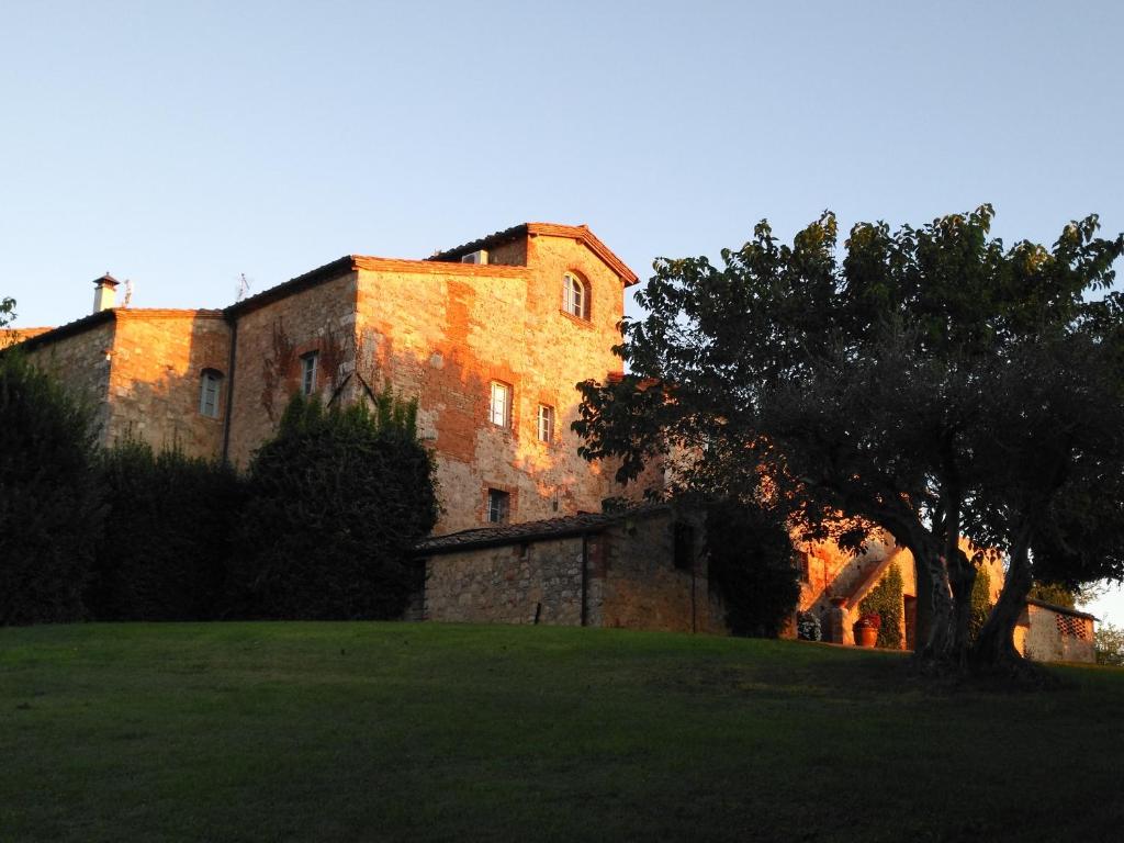 un viejo edificio de ladrillo con un árbol delante de él en Relais CastelBigozzi en Monteriggioni